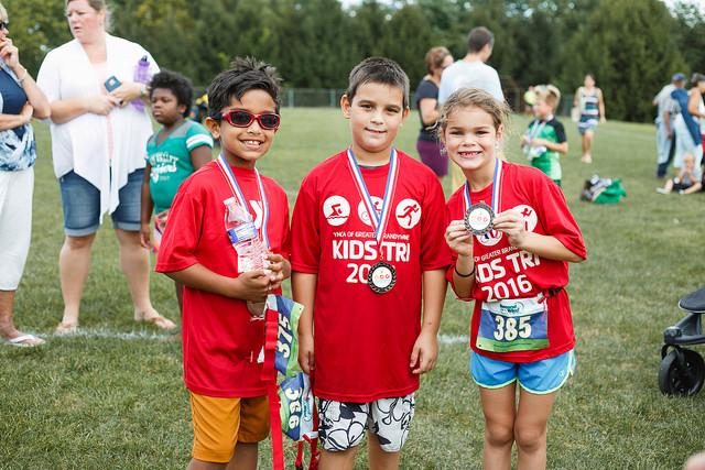Three kids smile with their medals after completing the 2016 kids triathlon at the Lionville Community YMCA in Exton, PA