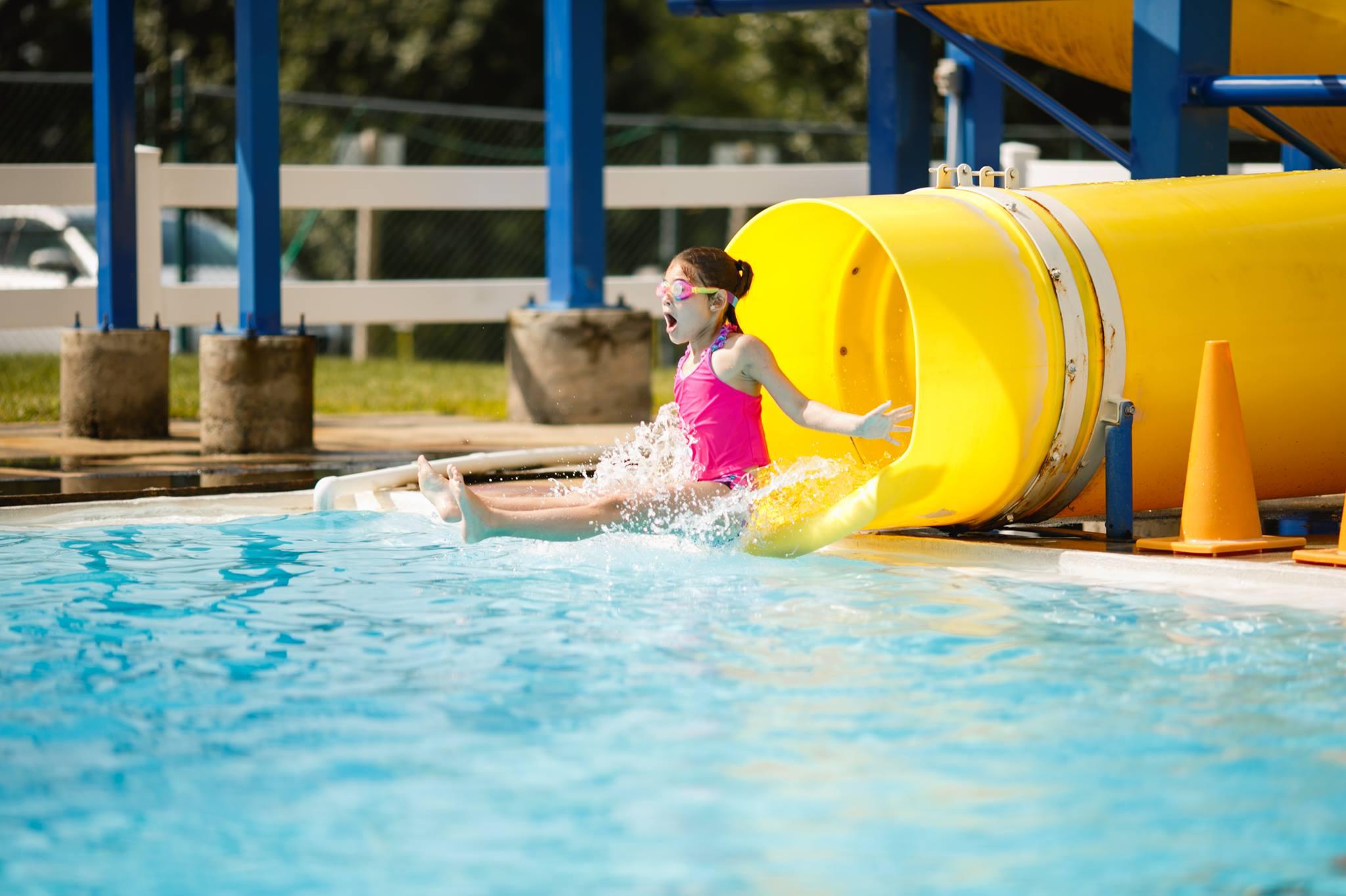A camper at Brandywine YMCA summer camp goes down the outdoor swimming pool water slide during camp swim time. 