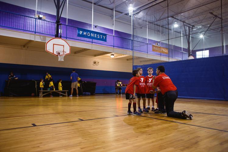 Youth Sports - A youth basketball team huddles up with their volunteer coach before the start of the basketball game at Kennett YMCA in Kennett Square, PA.