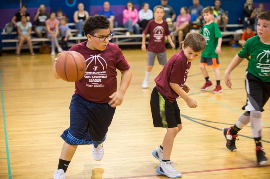 Youth basketball player dribbling a basketball during a YMCA youth sport league game. 