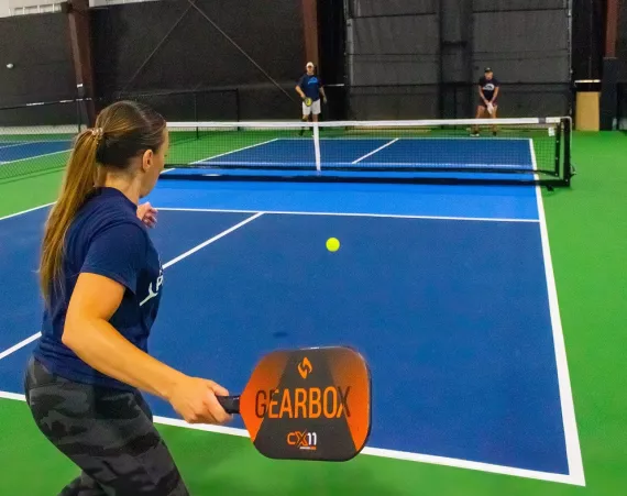 woman prepares to return a shot on an indoor pickleball court