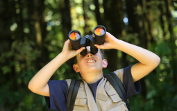 A boy uses binoculars to study birds during an environmental and nature program at the Upper Main Line YMCA in Berwyn, PA