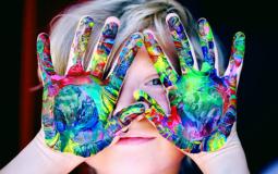 Young child with colorful paint on their hands. 