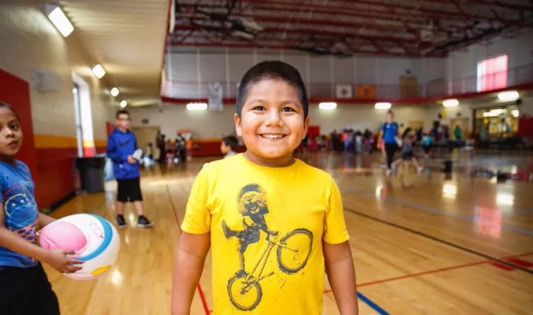 Boy smiling in the gym during the after school care program at  Oscar Lasko YMCA & Childcare Center