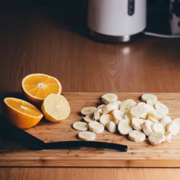 A cutting board with an orange and banana to make a healthy meal. 